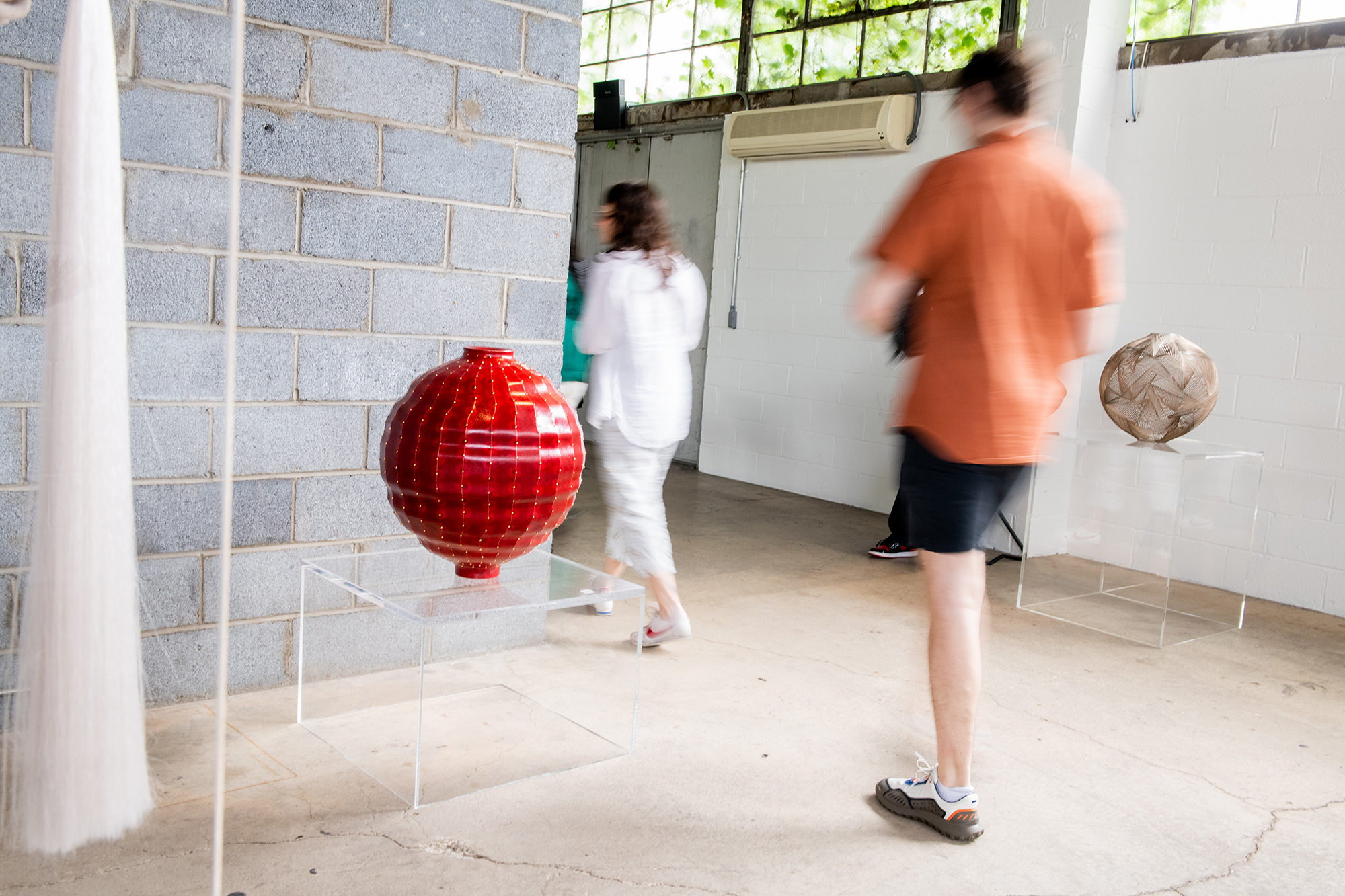 Gallery visitors observe the LOEWE FOUNDATION's Craft Prize exhibition, which included alumnus Jaiik Lee's Transition VII metal vessel design.