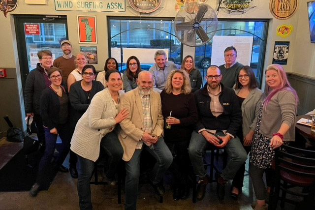 group of people posing for a photo in a bar.