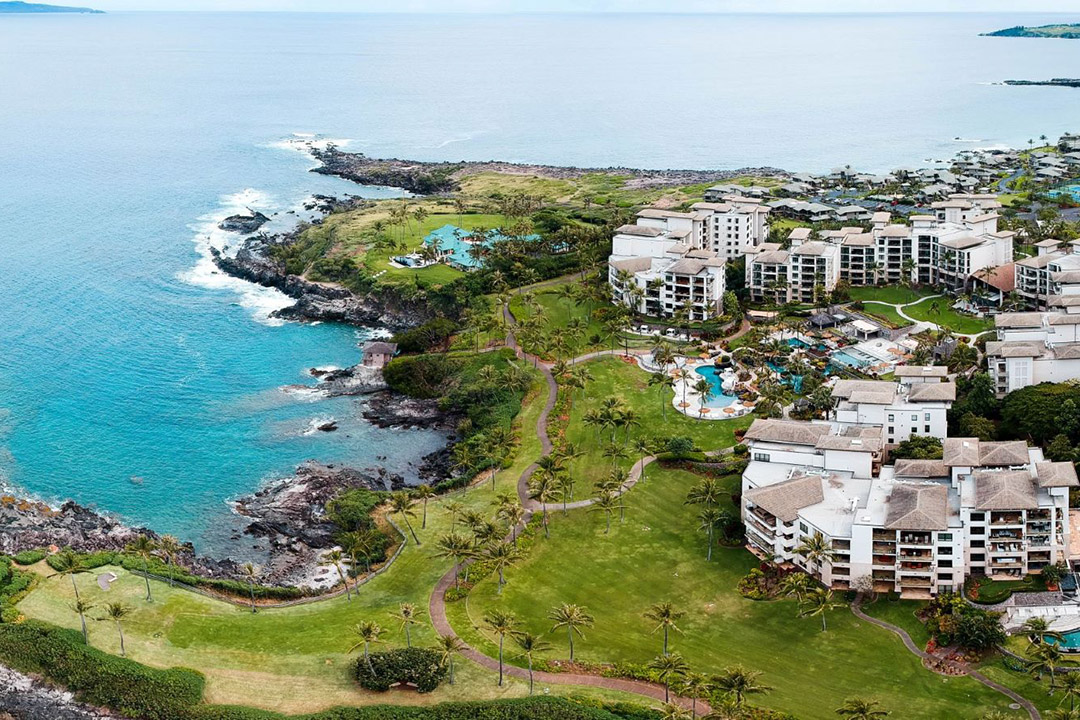 condo units surrounding a pool area near the coast of a body of water.