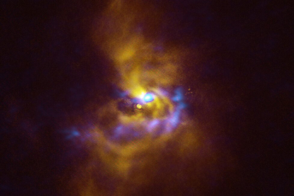 yellow and purple dust particle forming around a yellow orb in space.