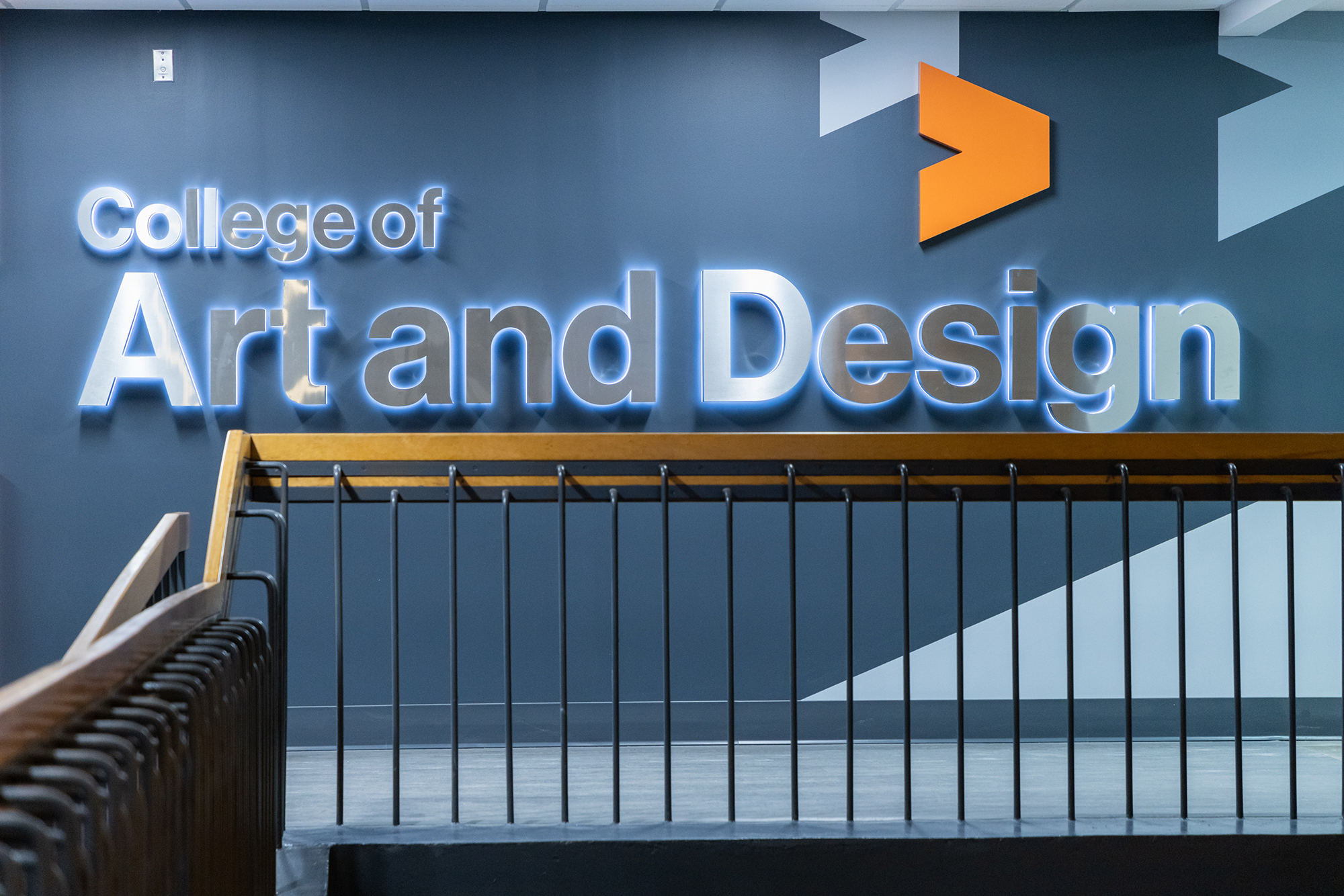 Wall signage with College of Art and Design in big, silver letters.