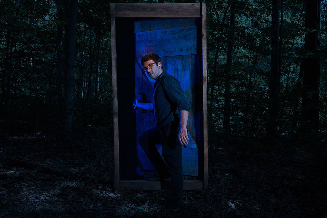 person opening a prop door in a dark forest.