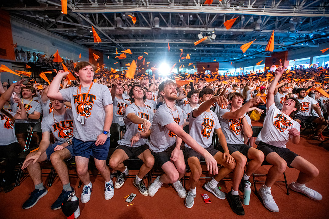 row of college students throwing paper airplanes.