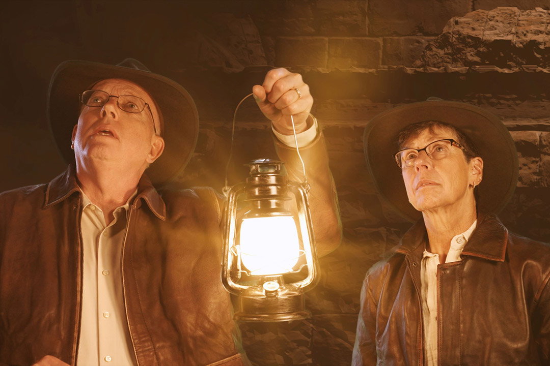 two people holding a lantern dressed like Indiana Jones.