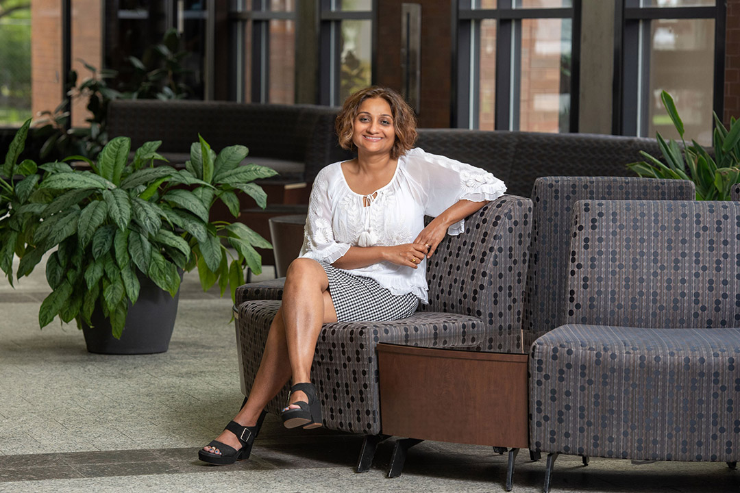 college professor sitting on a small sofa-like chair.