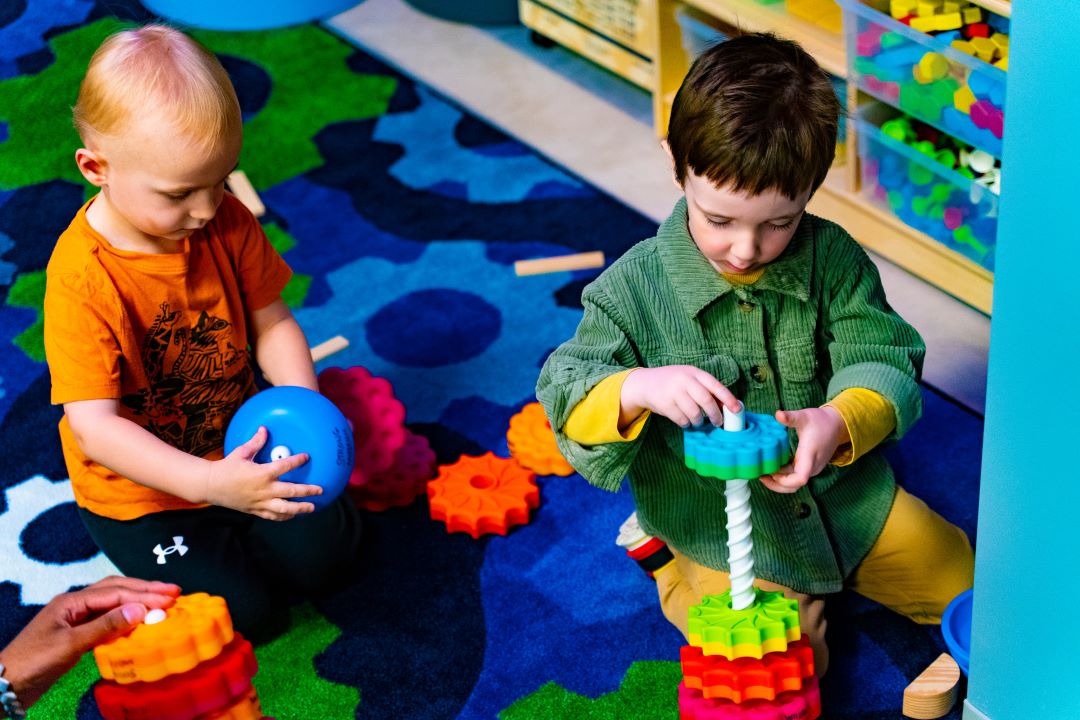 Two toddlers play with colorful plastic toys.