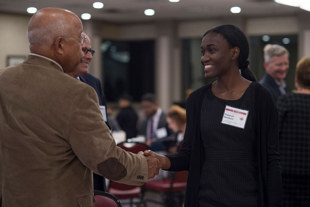 two people of color shaking hands at a reception event.