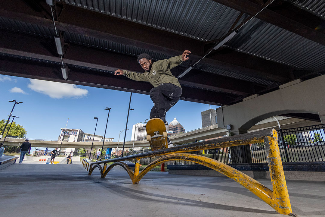 person on a skateboard sliding along a pipe at a skate park.