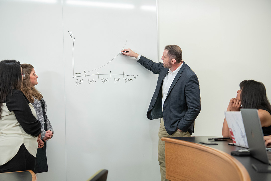 college professor drawing an upward curved line on a graph.