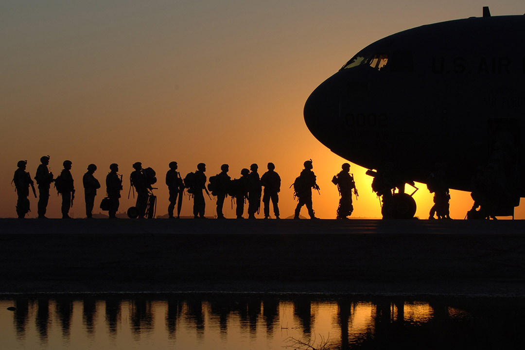 silhouette of soldiers in a line to board an aircraft.