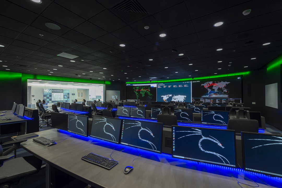 a computer lab with several rows of tables with computer screens.