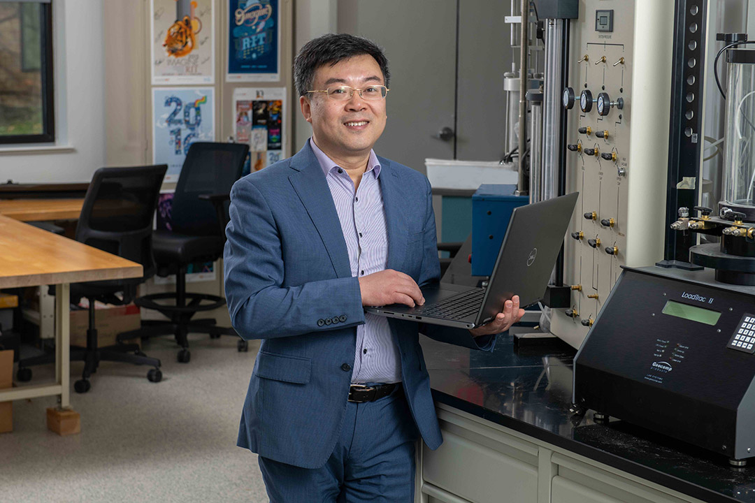 researcher holding a laptop in a lab.