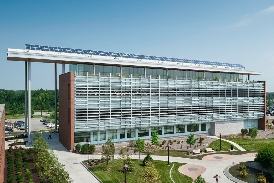 exterior of a three-story glass and brick building with solar panels on the roof.