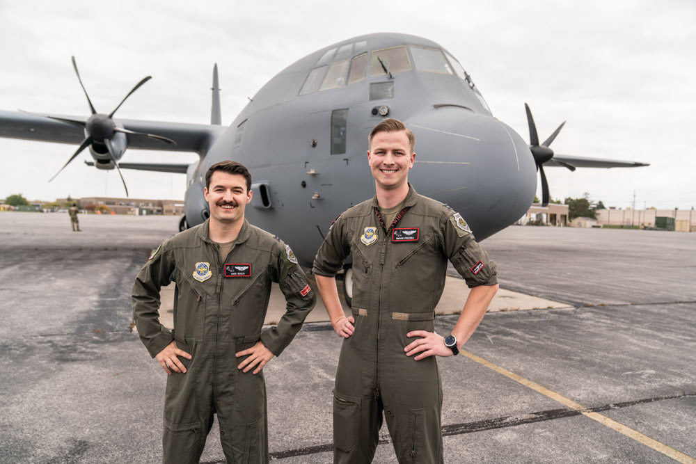 two Air Force pilots standing in front of a C 130 cargo plane.