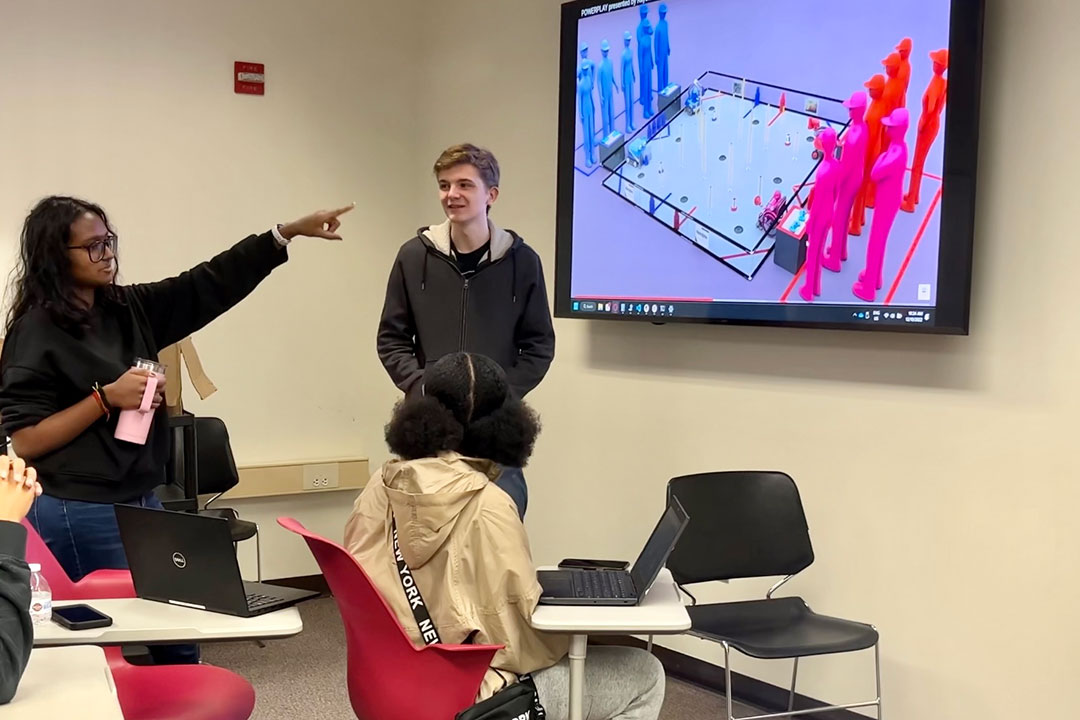 RIT students working with local youth by showing robotics project on a TV screen
