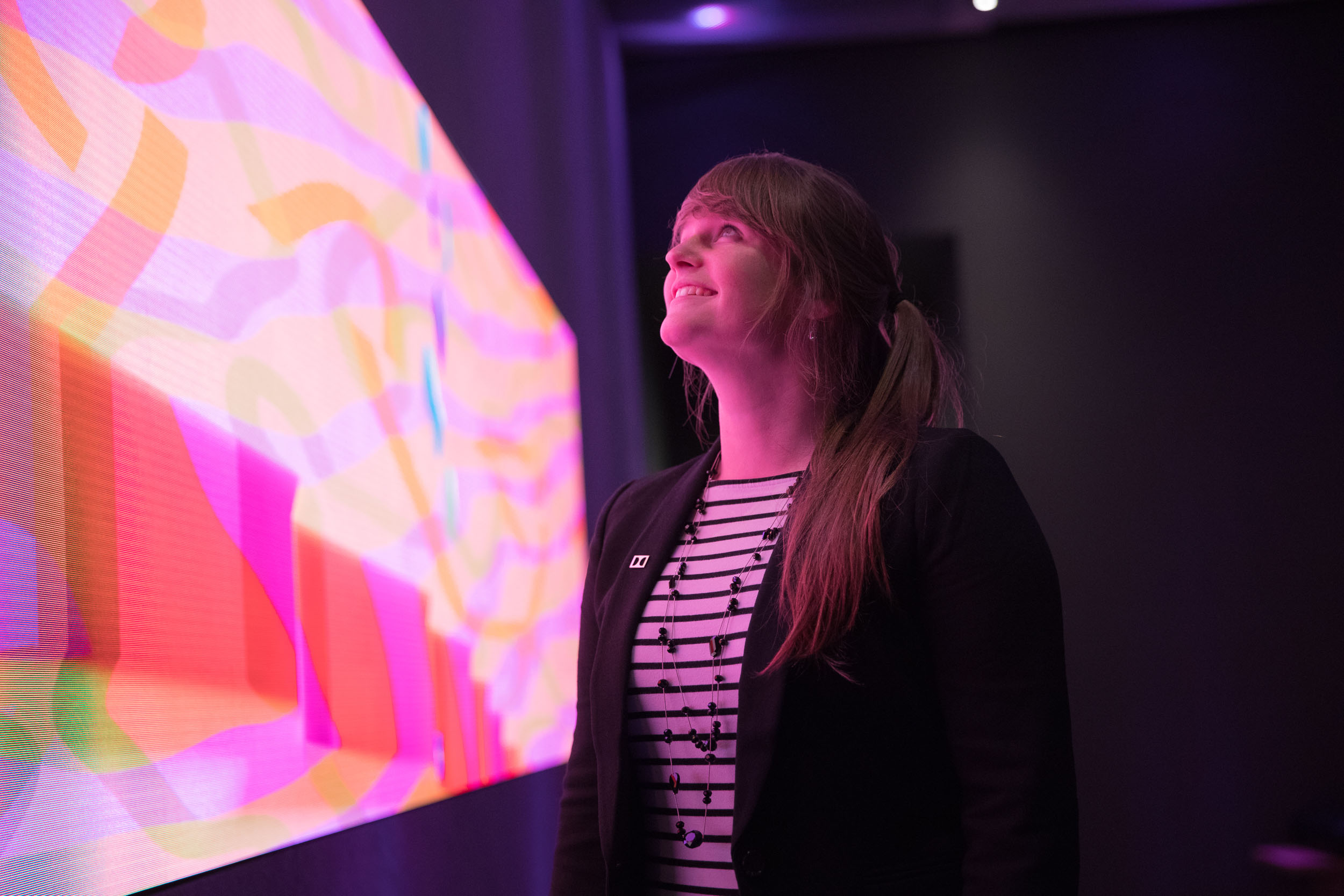 Jaclyn Pytlarz looks at a colorful, vibrant screen.