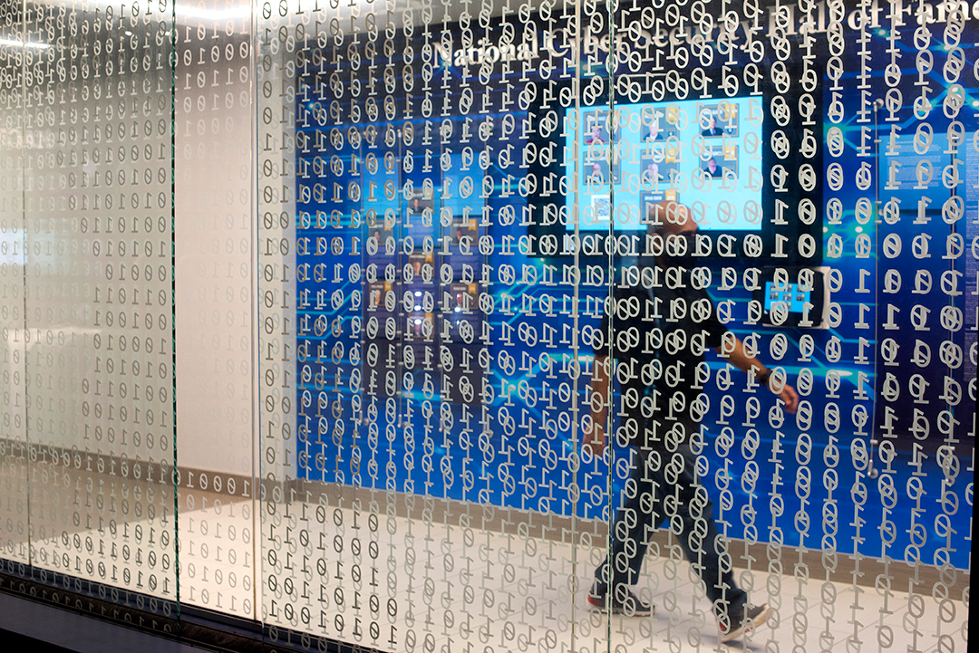 student walking past windows with binary code on them