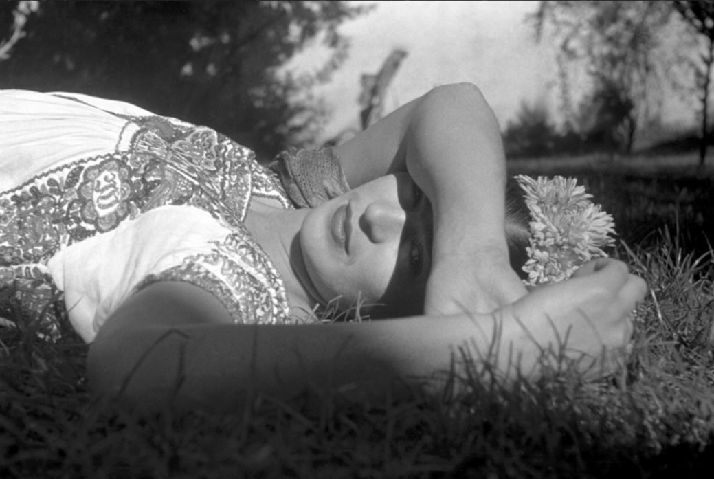 a black and white photo of Mexican artist Frida Kahlo laying in the sun with her arm blocking her eyes from the rays