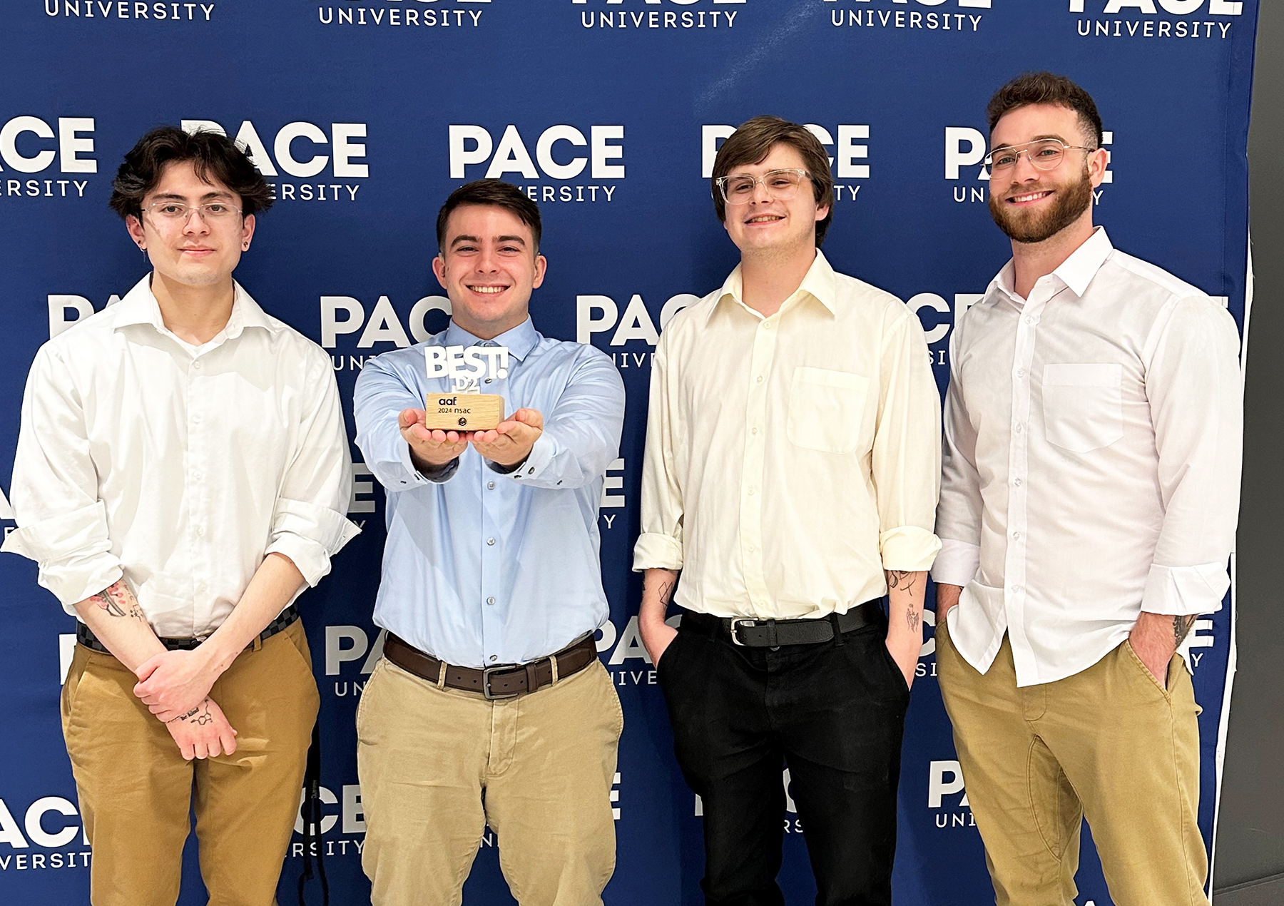four advertising and public relations students stand together at the conference posing with their new award