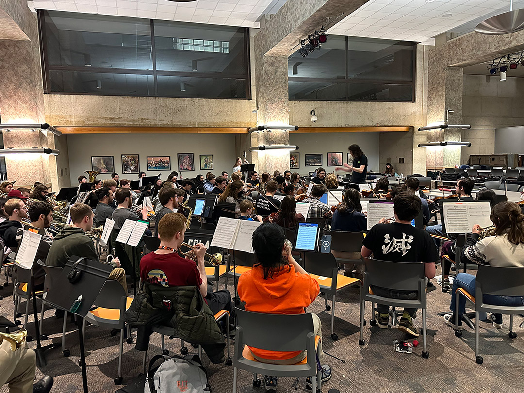 RIT’s Game Symphony Orchestra is shown rehearsing in a performance room.