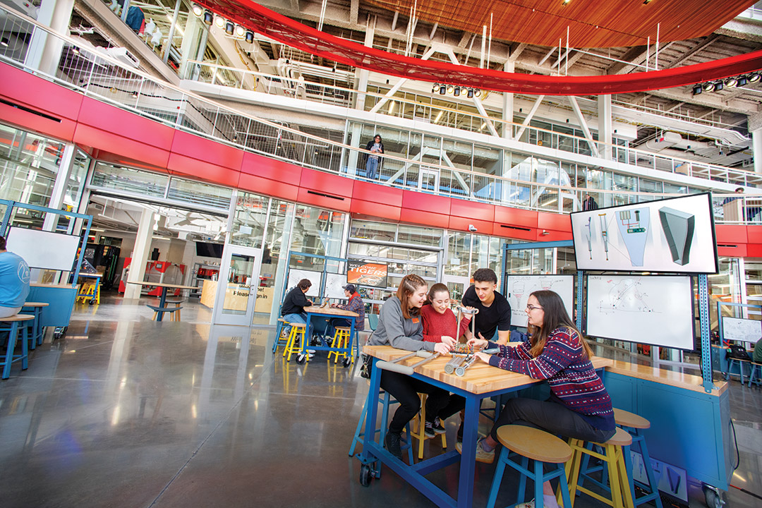 four students sit at a table testing a small product in one of the SHEDs makerspaces.