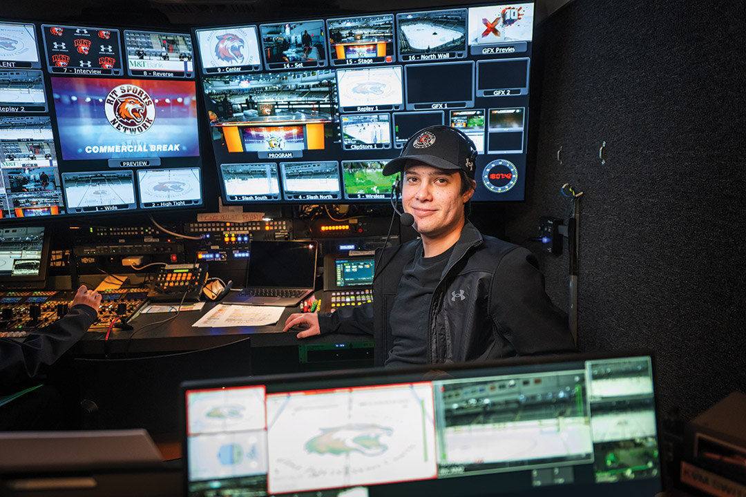 a student sits in front of and behind monitors.