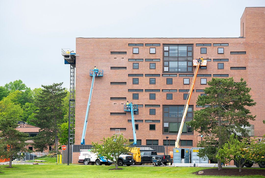 Construction workers are shown working on the face of a five story residence hall.