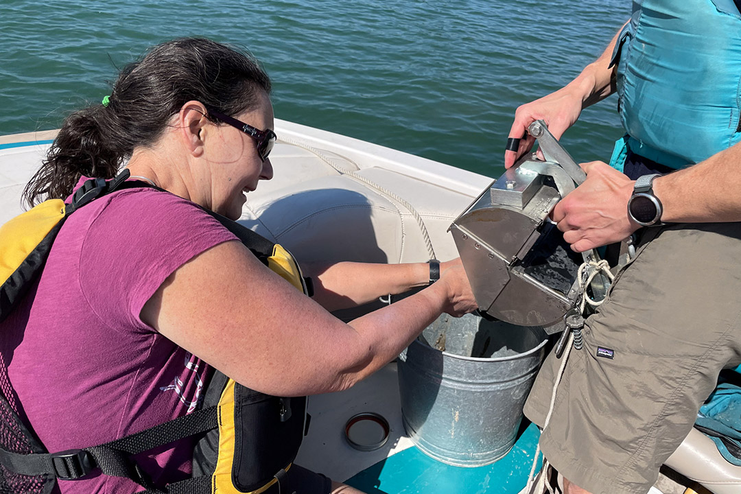 A woman samples sediment in Lake Ontario as part of her extensive research in marine debris. 