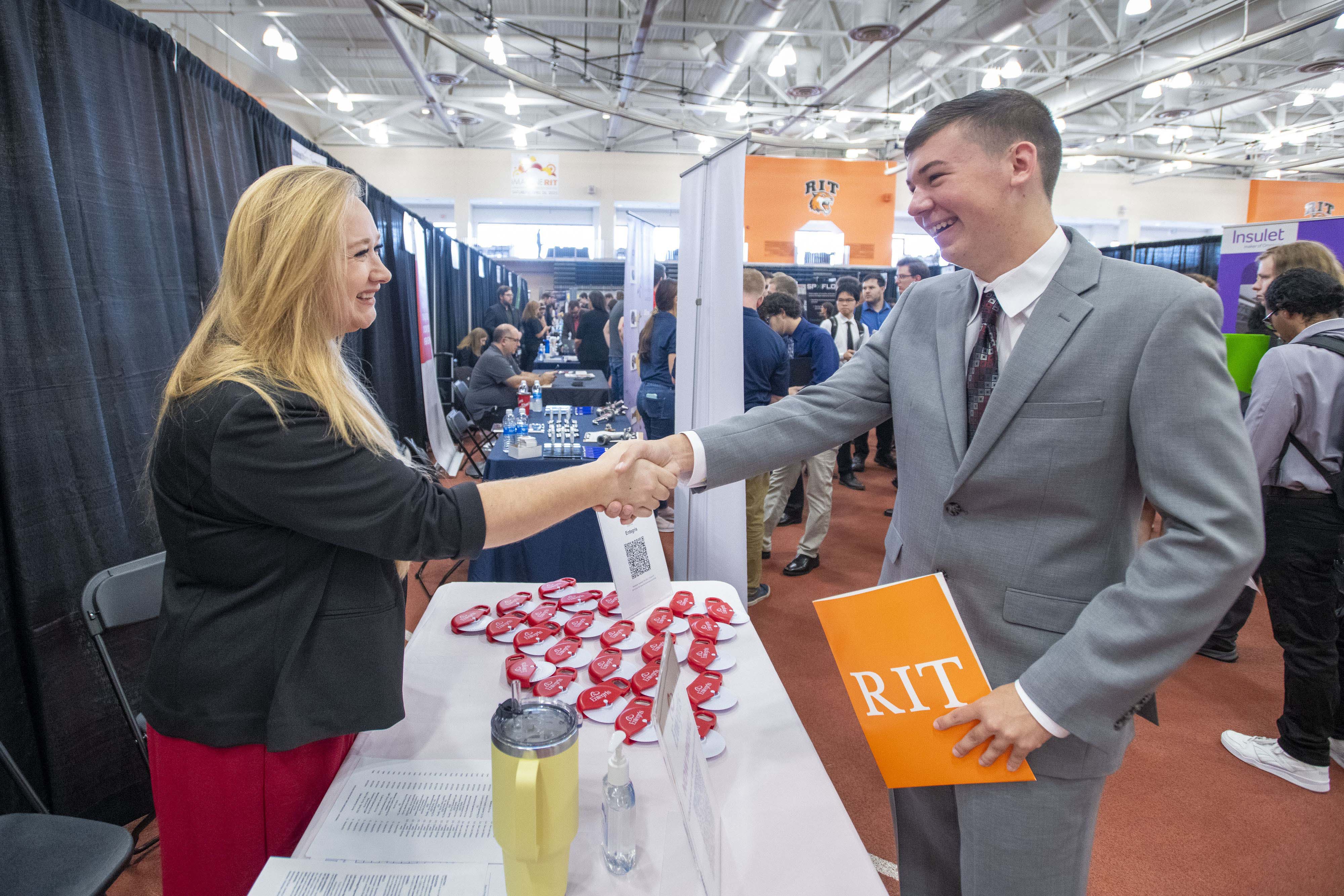 A student and shakes hands with a business representative