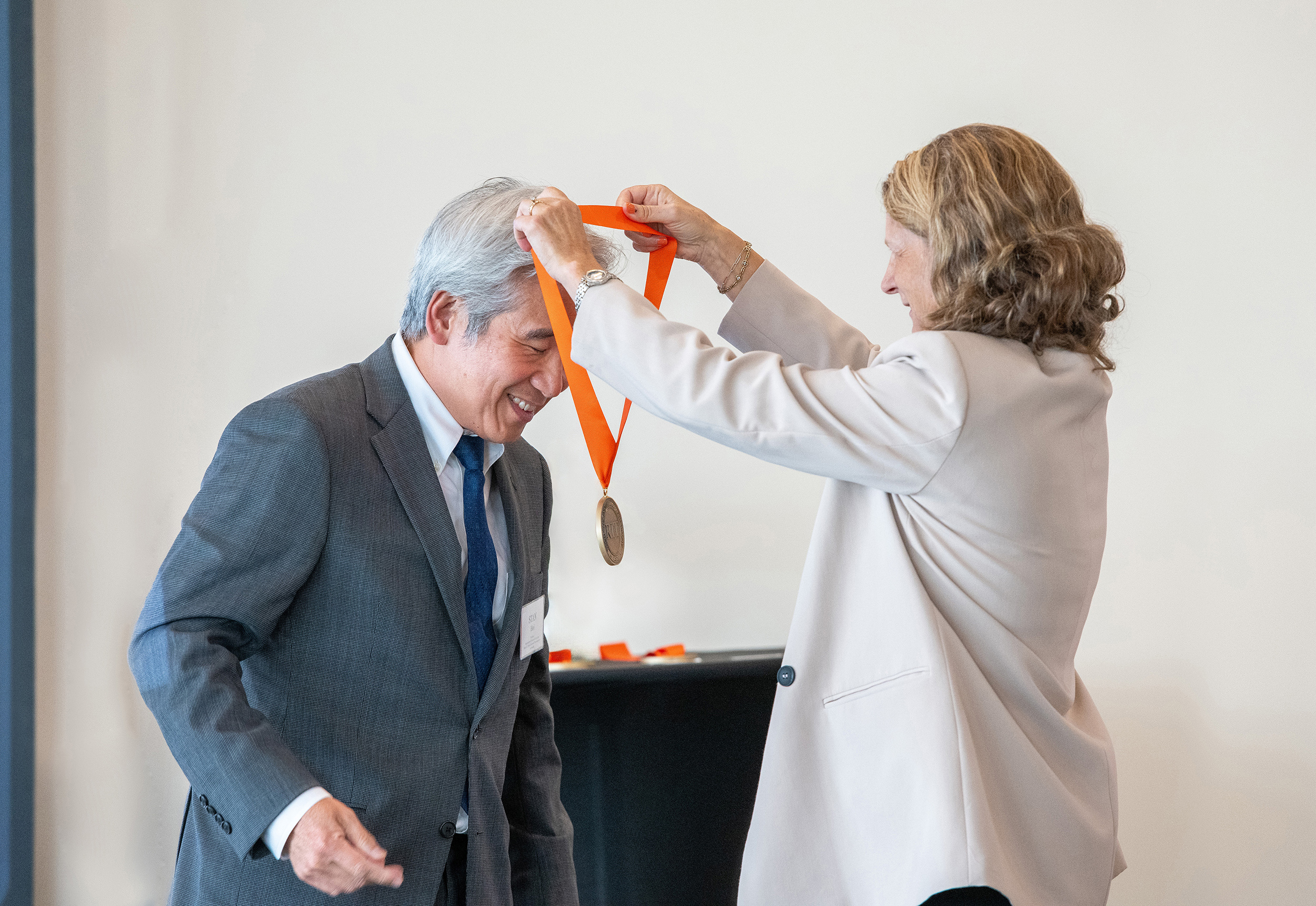 A man in a suit bends to recieve a medal