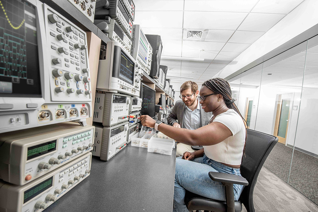 Michael Zuzak works with student Sydale John Ayi in a research lab filled with computer equipment