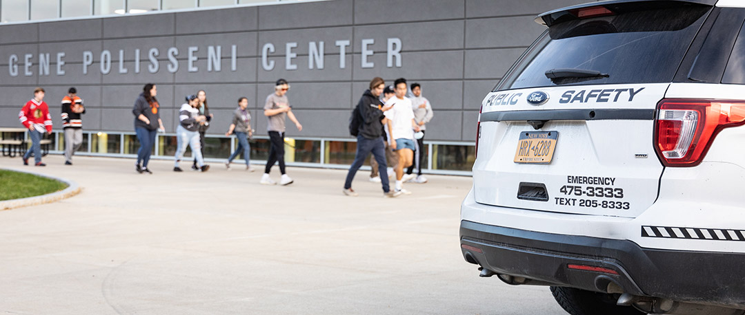 a white SUV that has Public Safety logos on it sits in front of the Gene Polisseni Center.