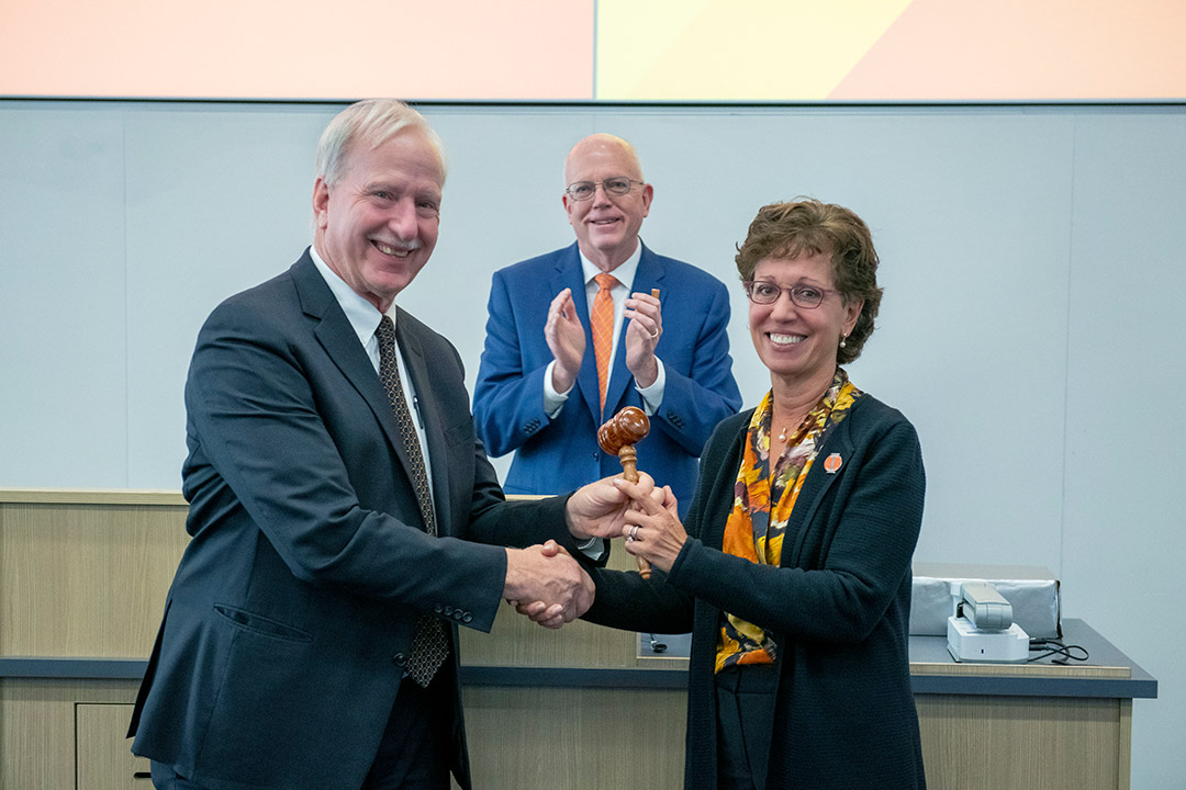 a man and woman shake hands in front of R I T President David Munson.