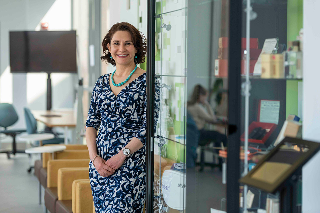 Blanca Lapizco-Encinas stands in a blue and white dress in the doorway of a room with glass walls.