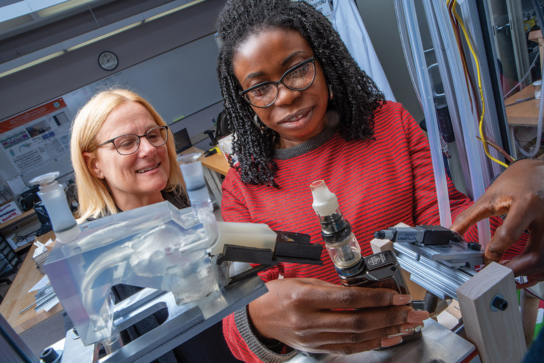 Risa Robinson works with student Gloria Mbaka in a lab.