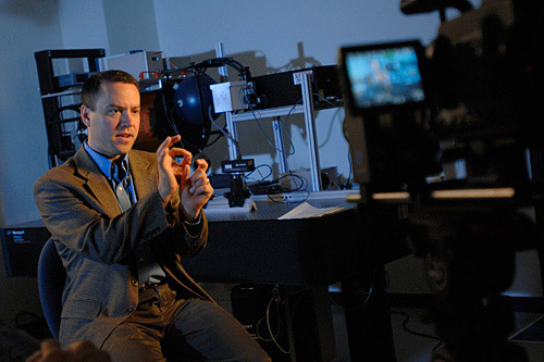 man in a lab explaining a science concept in front of a T V camera.