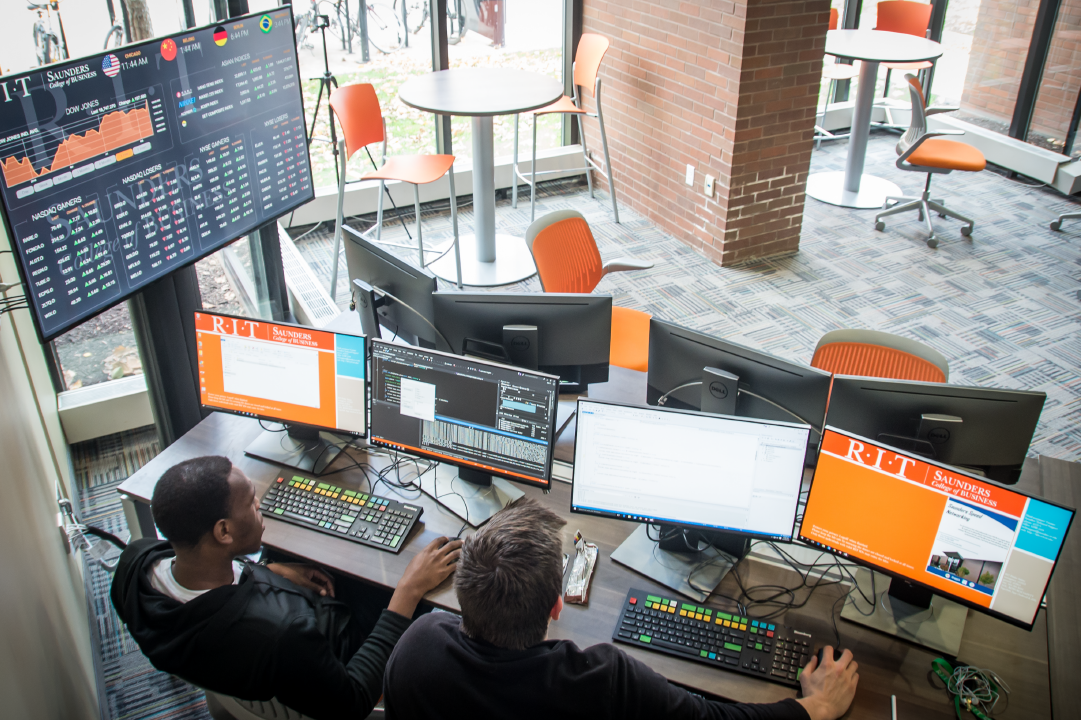 students working on several computer monitors in a business lab.