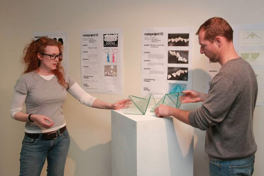 Student showing off their triangular glass design to another person.