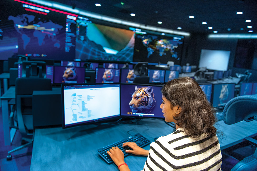 a college age girl works at a computer in the cybersecurity lab.