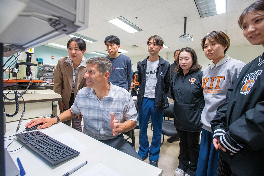 Students stand with professors Karl Hirschman, seated, and Jing Zhang, far left.