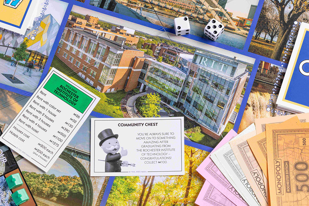 A close-up of the Monopoly Rochester Edition board featuring the Rochester Institute of Technology property card, a Community Chest card, dice, Monopoly money, and various game pieces on a colorful board with local landmarks.