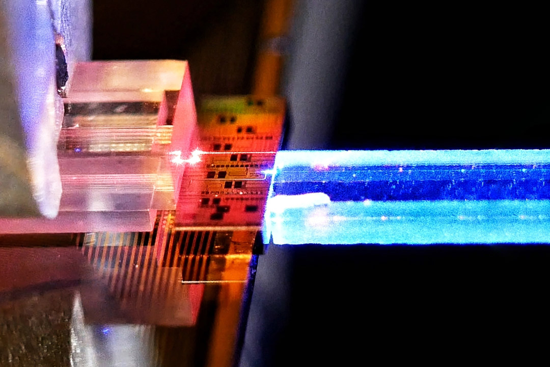 Close-up of a prism with colorful light beams and electronic circuitry.