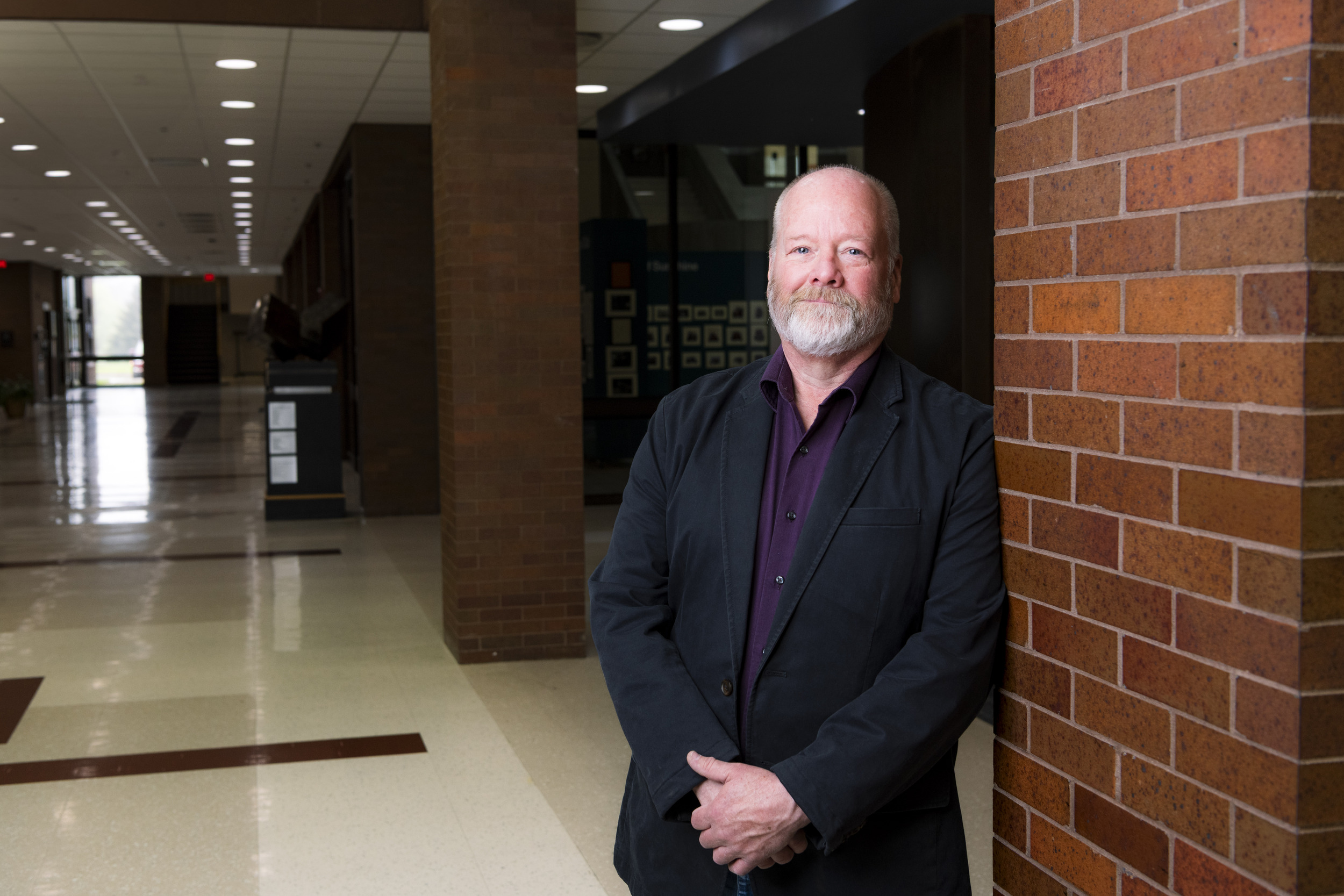 A man leans against a brick wall