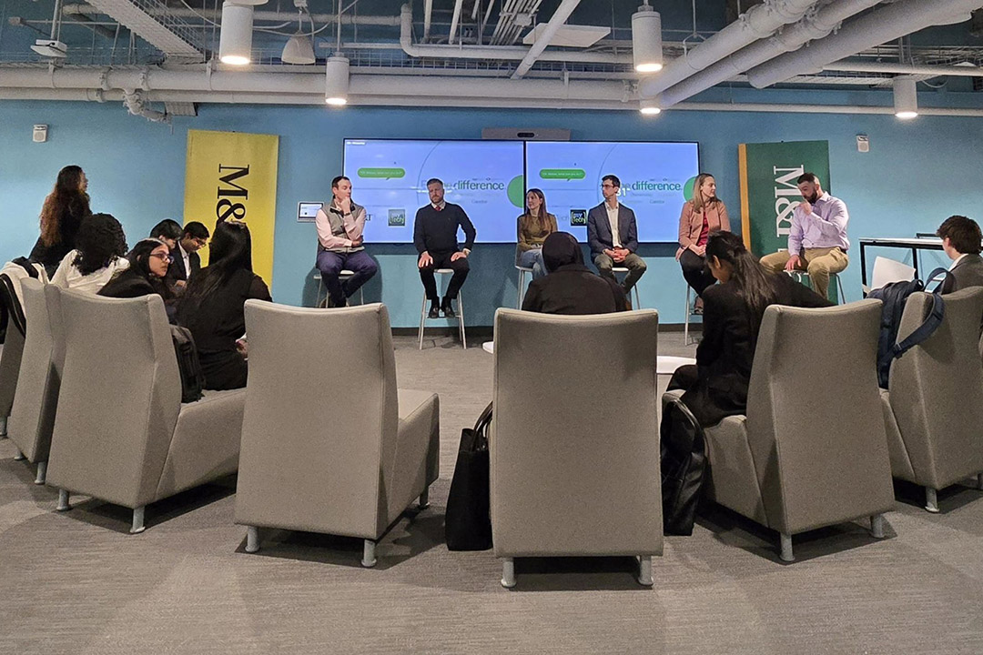 students seated in gray chairs forming a semicircle look at mentors sitting on a panel discussing their jobs.
