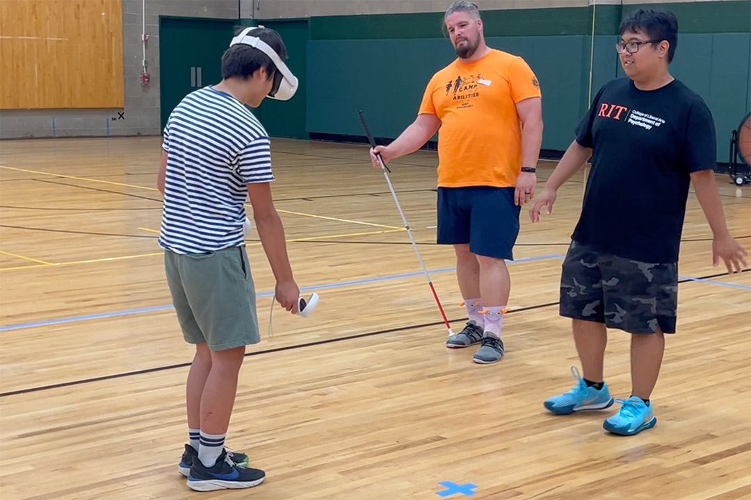 two people work on cane skills with a visually impaired person using a game developed to assist children in orientation and mobility. 