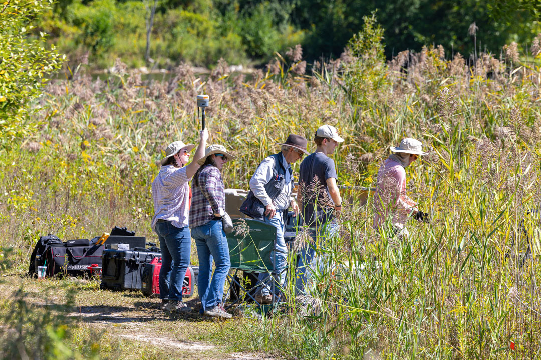 RIT students and researchers work to set up ground-based data collection instruments in the wetlands area of Tait Preserve