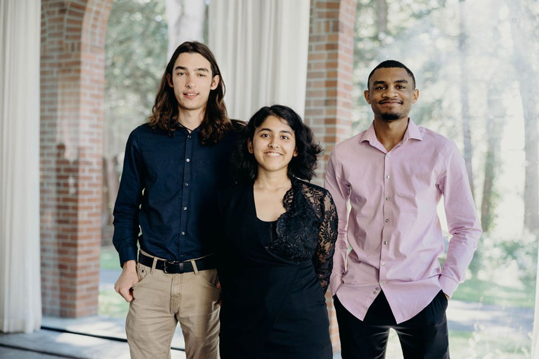 three people stand in a sunlit outdoor atrium