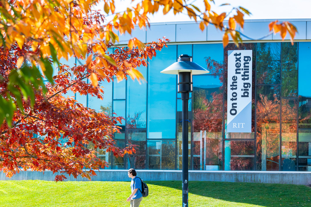 a student walks on the RIT campus in the fall.