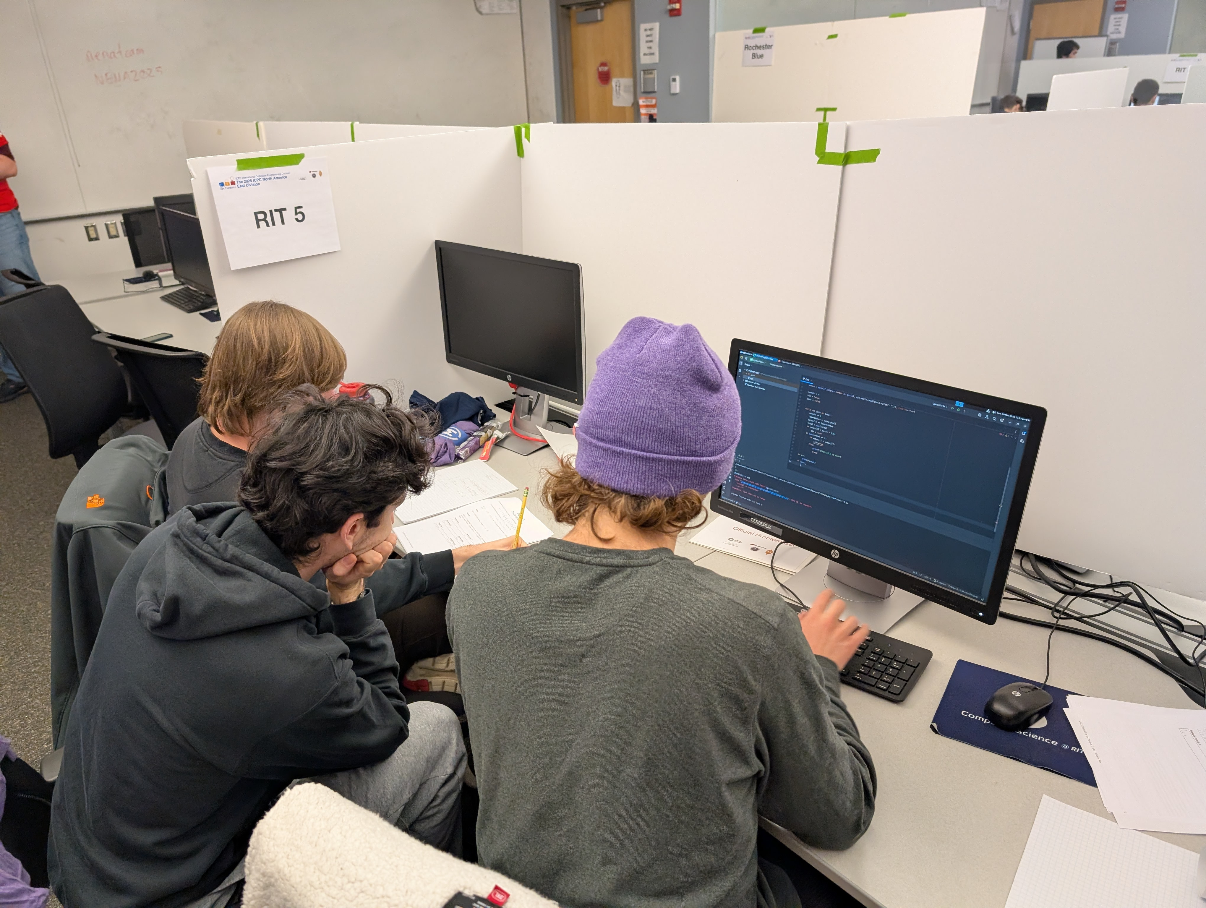 Three RIT students working around a computer