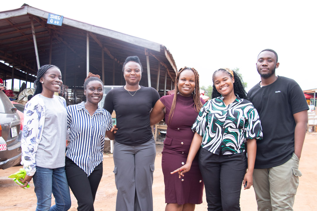 a group of 6 people stand in a village in a remote area.